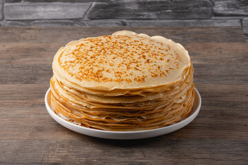 Thin pancakes on a wood table. Homemade crepes, tasty food. Staple of yeast pancakes, traditional for Russian pancake week (Shrove tide). Thin pancake with crispy crus