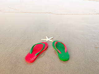 green and red sandals on summer beach background at sunset with copy space.