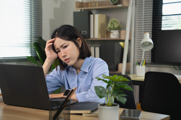 Obraz premium Stressed Asian Businesswoman Suffering from Headache and Overwork in Home Office