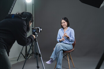 Behind the scenes of a young Asian woman being filmed for a video interview in a professional studio