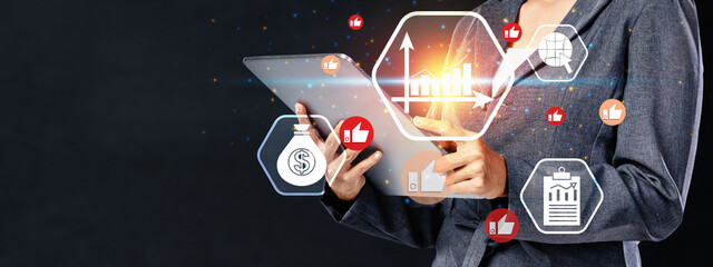 Businesswoman in a suit holding a tablet displays financial data, charts, and symbols. Concept of business analytics, success, and digital technology