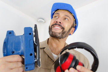 man sanding a wood with sander in a workshop