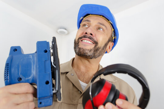 man sanding a wood with sander in a workshop - Powered by Adobe