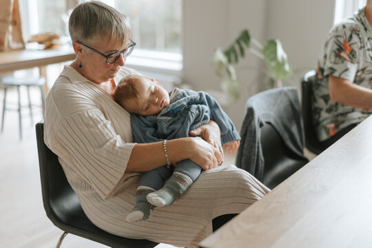 High angle view of grandmother sitting with sleeping grandson at home