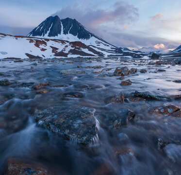 Scenic view of stream with snowy mountains in background against sky