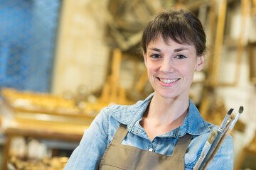 happy woman holding brushes in art department
