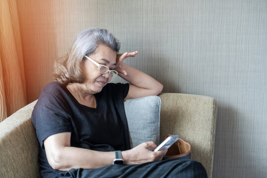 Menopause senior woman with anxiety disorder, mental health illness, stressful depressed aging female person with headache and migraine usine mobile phone tiredly at home - Powered by Adobe