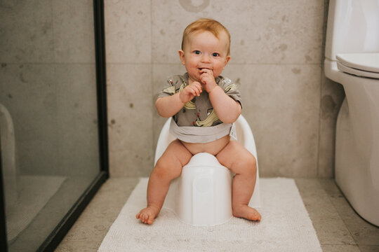 Portrait of cute boy sitting on potty seat in bathroom