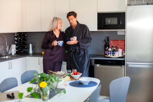 Senior couple spending leisure time having coffee in kitchen at home