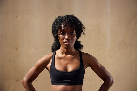 Young female athlete with curly hair against wall