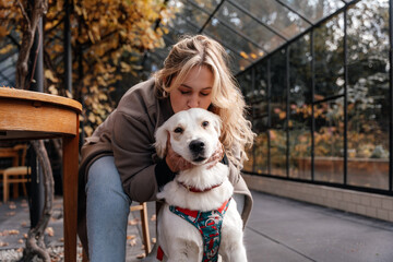 Young woman hugging golden retriever at pet-friendly cafe in glass greenhouse