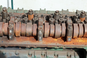 ​A close-up shot of weathered, teal-painted engine pulleys and belts, showing rust, texture, and remnants of red paint in bright sunlight.
