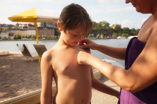 Mother putting bandage on shirtless son's chest