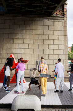 Young man breakdancing around male and female friends on platform