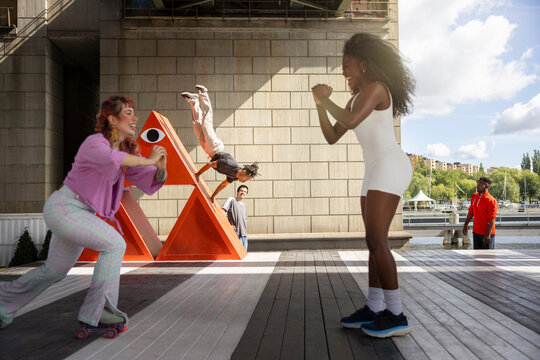 Female friends enjoying with each other while man balancing on red structure