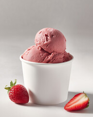 Strawberry gelato in the whit paper cup. Food advertising photo.