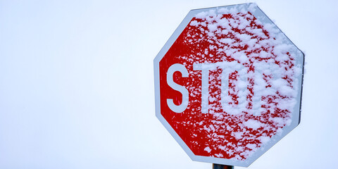 Segnaletica stradale con simbolo di STOP ticoperta di neve in un paesaggio invernale imbiancato di neve