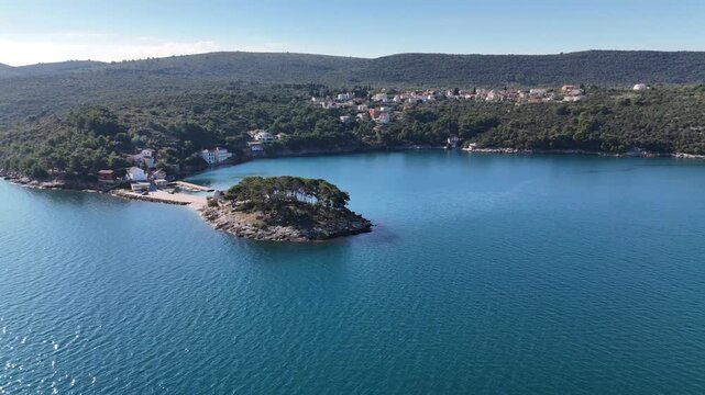 Drone circles a small inlet in Savar on Dugi Otok, revealing a tiny church and the turquoise Adriatic Sea with scenic coastal views.