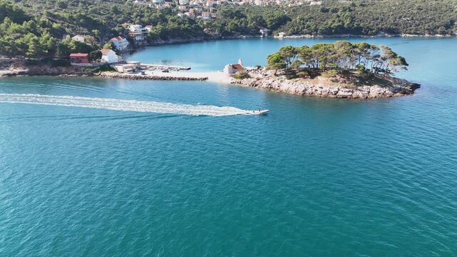 Drone approaches a speed boat near a tiny island in Savar, Dugi Otok, capturing turquoise Adriatic waters, scenic coastline, and boating adventure from above.