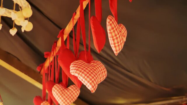 Red gingham and cotton hearts sway above in warm tilted-up cafe ceiling shot