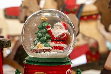 A glass ball with a Santa Claus and Christmas tree figurine inside