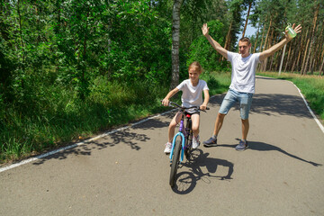 Dad teaches daughter to ride a bike. Girl sat on bicycle for the first time, his father teaches child to ride a bicycle.