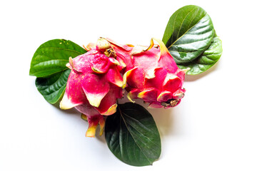 Two pitaya fruits with green leaves on white table. Tropical fruits food, top view