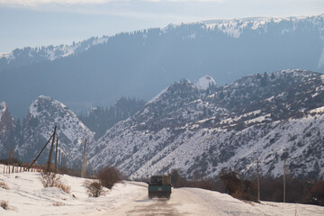 Jeti-Oguz, Kyrgyzstan - December 13, 2024: A vehicle driving on a snowy road with the famous Broken Heart red rock formation in the background