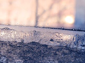Beautiful ice pattern and sunlight on window glass, natural winter background