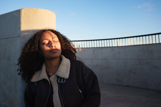 Woman leaning on wall with eyes closed