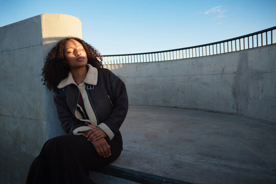 Woman leaning on wall with eyes closed while sitting on floor