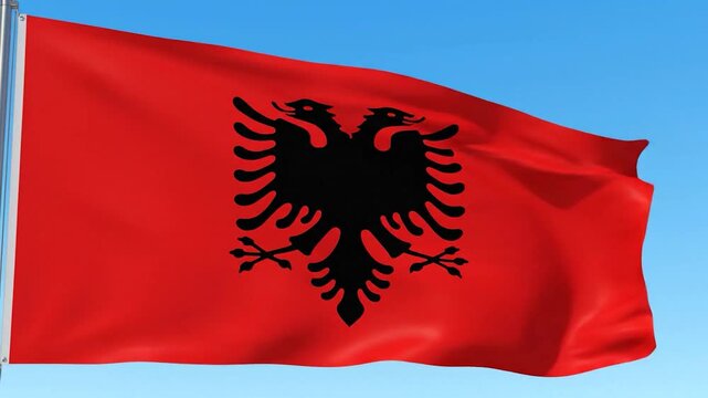 A vibrant red flag with a striking black two-headed eagle emblem under a blue sky