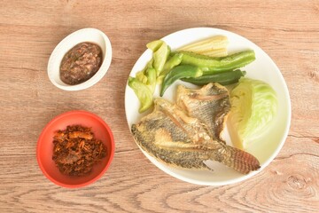 batter fried tilapia fish with boiled vegetable on plate dipping spicy shrimp paste sauce