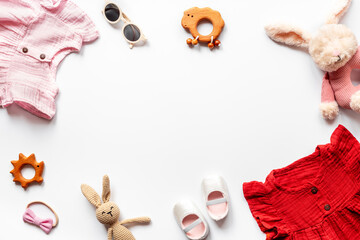 Flat lay frame of summer clothes for baby girl - pink and red cotton muslin dress with accessories, top view