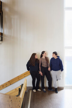 Smiling male and female friends spending leisure time talking with each other in school building
