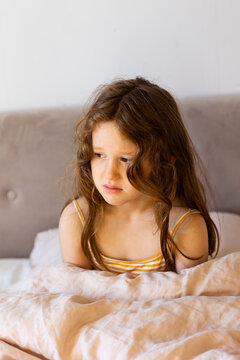 Sad girl sitting on bed at home