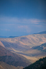Telephoto view of rolling mountain ranges fading into the distance with textured slopes and atmospheric blue haze