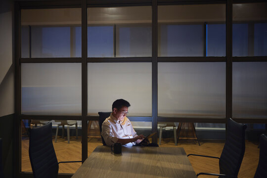 Businessman using tablet PC while working late in office conference room