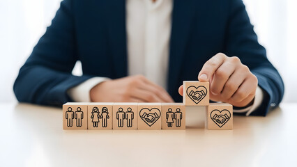 Business person carefully building a tower of wooden blocks with people icons