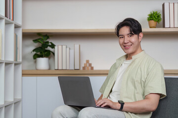 Digital Engagement. Smiling young man using laptop in a cozy home environment.