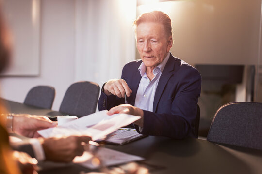 Senior businessman giving document reports to colleague in meeting at office