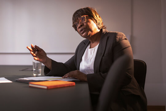 Mature businesswoman gesturing while explaining financial report in meeting at office