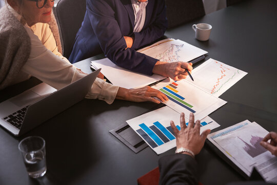 High angle view of business experts analyzing data graphs on conference table in meeting at office