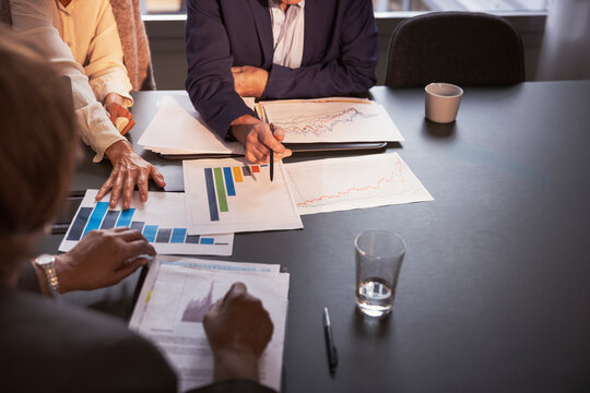 High angle view of business professionals analyzing bar graphs on conference table in meeting at office