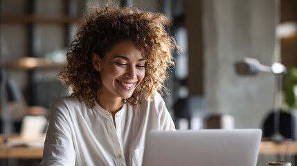 A picture of a cozy home office with warm lighting shows a female freelancer quietly reading an encouraging email, expressing relief and happiness.