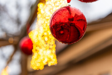 Close up of festive Christmas decorations on the street featuring a glowing star and a red bauble glowing softly on a rainy evening