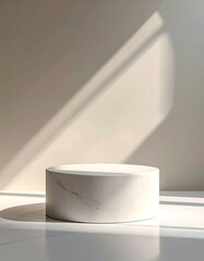 A minimalist white marble cylindrical podium on a reflective surface with strong diagonal shadows, ideal for product display.