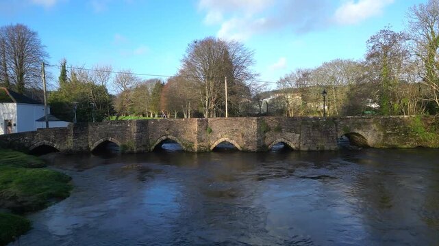 Lostwithiel, Cornwall, England: DRONE VIEWS: The drone approaches Lostwithiel Bridge low over the surface of the River Fowey. The bridge is a Grade 1 listed structure built in the early 14th century.
