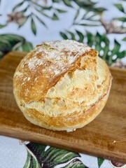 Crispy and rustic round loaf bread on a wooden board. Bread in the countryside