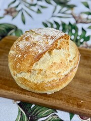 Crispy and rustic round loaf bread on a wooden board. Bread in the countryside